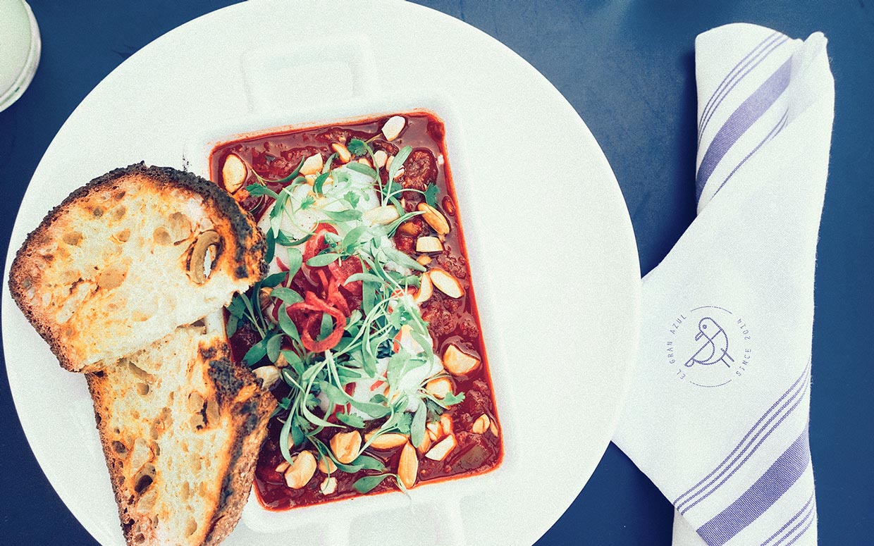 A white plate with soup and bread